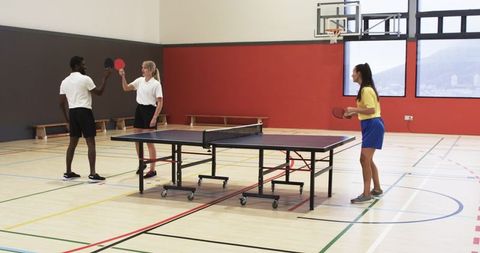 Friends enjoying table tennis game in indoor recreation center