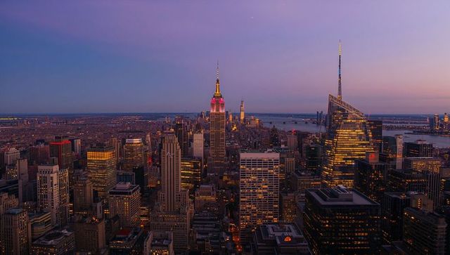 Midtown nyc skyline glowing at twilight with empire state lit crown and waterfront panorama