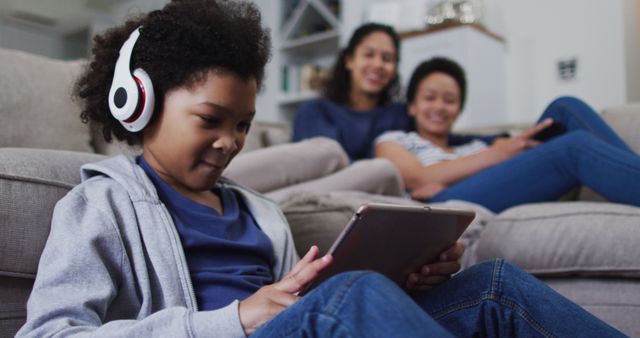 Young Boy Wearing Headphones Using Tablet with Family in Background - Download Free Stock Images Pikwizard.com