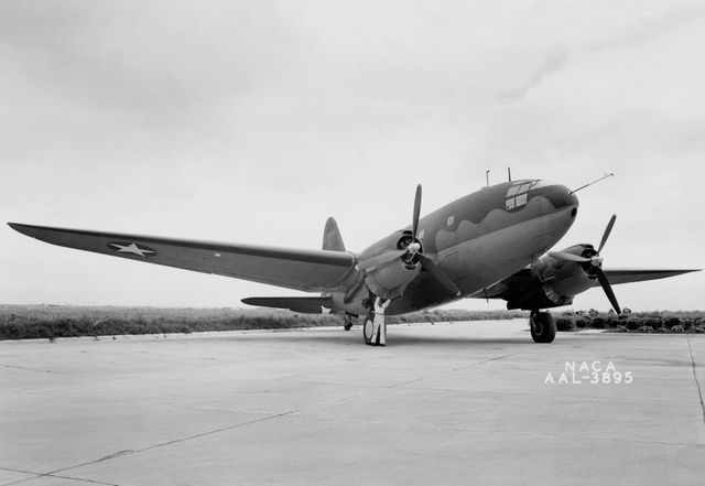 This vintage black and white image showcases a Curtiss C-46 aircraft on a runway with thermal ice-prevention equipment installed. The C-46 Commando, widely used during World War II, is important in aviation history. Perfect for educational articles, historical documentation, aviation technology presentations, and military history resources.