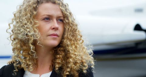 Thoughtful businesswoman with curly hair at airport tarmac