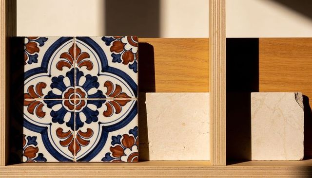 Displaying glazed ceramic floral tile on plywood shelf with beige stone tiles and shadows