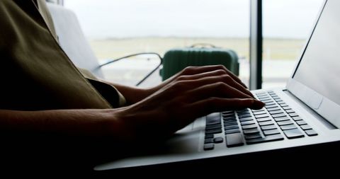 Close-up of hands typing on laptop at airport gate