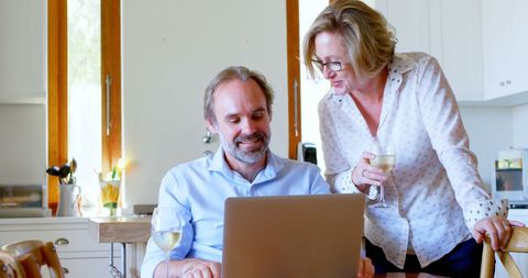 Happy Couple Relaxing at Home with Laptop in Kitchen