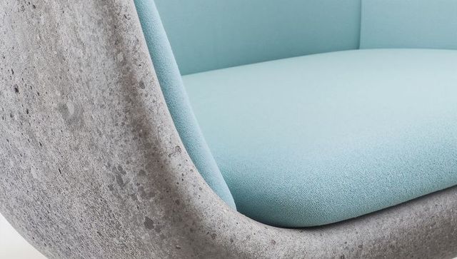 Blending concrete-textured shell with pastel blue upholstery on sculptural lounge chair