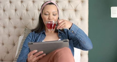 Woman Relaxing with Tablet and Tea in Cozy Bedroom