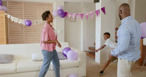 African American Family Celebrating Birthday Playing With Purple Balloons in Living Room