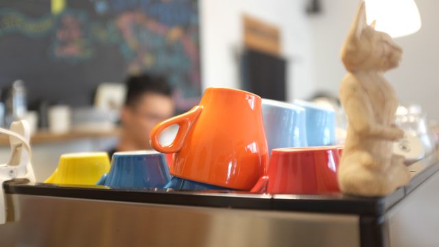 Brightly colored coffee cups arranged in a cozy café, ideal for conveying a warm, inviting atmosphere. Excellent for use in marketing materials, blog posts about coffee culture, or social media content highlighting cozy café experiences.
