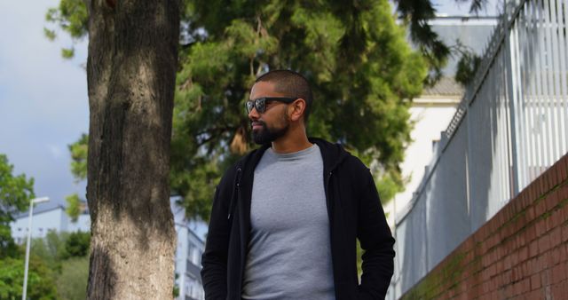 Confident Man Walking in Urban Park Wearing Sunglasses - Download Free Stock Images Pikwizard.com