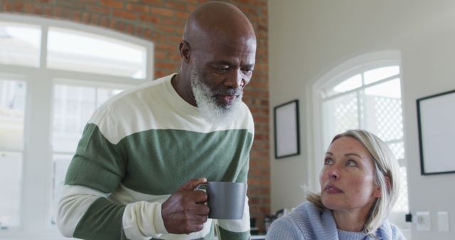 Stressed senior diverse couple in kitchen sitting at table, using laptop. retirement lifestyle, at home with technology.