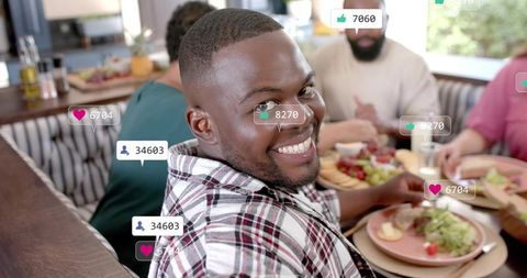 Smiling man turning to camera during group dining with social media likes overlay