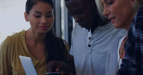 Diverse Team Collaborating on Tech Devices in Office Environment