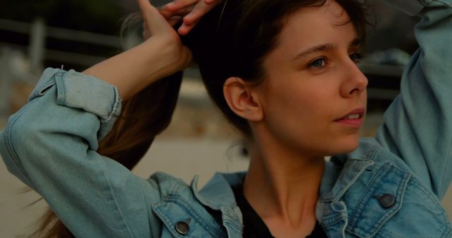 Portrait of Young Woman Adjusting Hair Outdoors in Denim Jacket - Download Free Stock Images Pikwizard.com