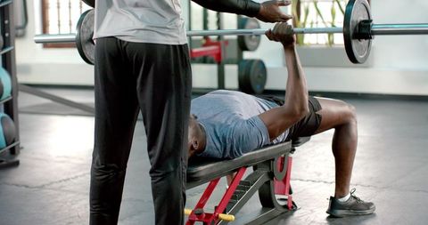 African american man bench pressing with spotter in gym training strength and discipline