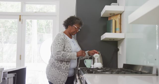 Senior african american woman preparing coffee in kitchen. Senior lifestyle, free time and domestic life.