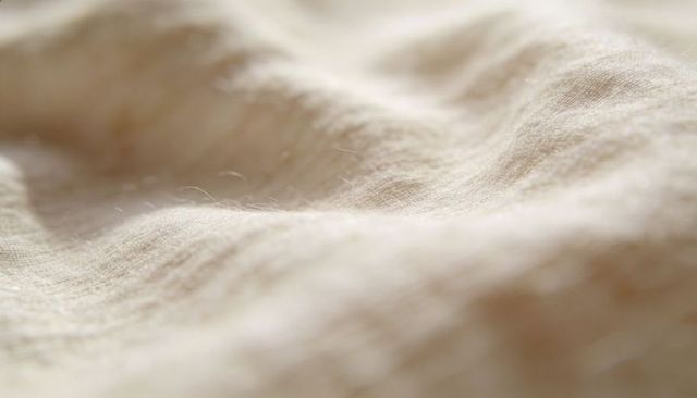 Macro linen fabric showing woven texture and loose fibers in soft neutral tones