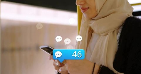 Muslim woman wearing beige hijab checking smartphone showing 46 message notifications