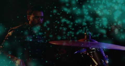 Playing male drummer on intimate club stage with teal bokeh, moody spotlight atmosphere