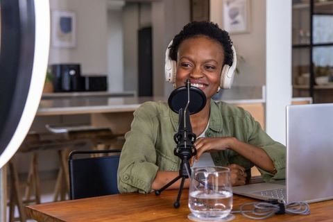 African american woman recording podcast at home studio with laptop and ring light