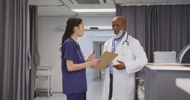 Shows a male doctor and a female nurse discussing a patient chart in a hospital. Ideal for illustrating healthcare, medical teamwork, hospital environments, and professional communication in healthcare settings.