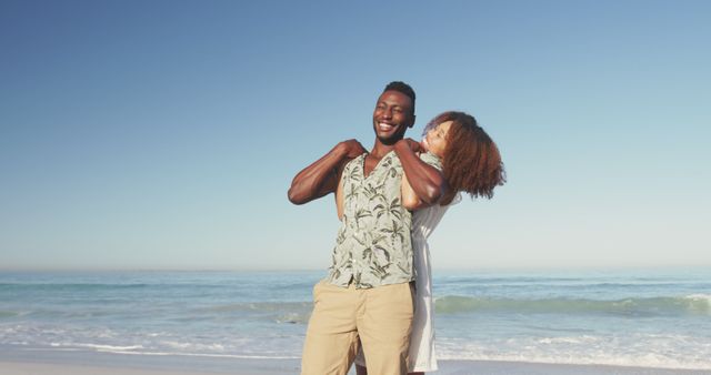 Happy diverse couple embracing and laughing, having fun on sunny beach by the sea. Summer, free time, relaxation, romance and vacations.