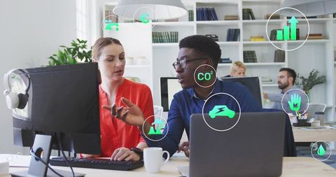 Collaborating on sustainability dashboard with floating eco icons in modern office workspace