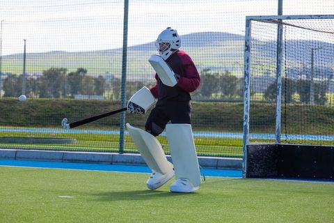 Field hockey goalkeeper ready to defend goal on turf field