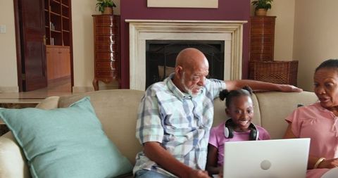 Grandparents and Granddaughter Using Laptop at Home