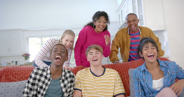 Happy diverse group of teenage friends sitting on couch and laughing at home - Download Free Stock Photos Pikwizard.com