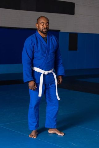 Mature Man in Blue Gi Preparing for Martial Arts Practice