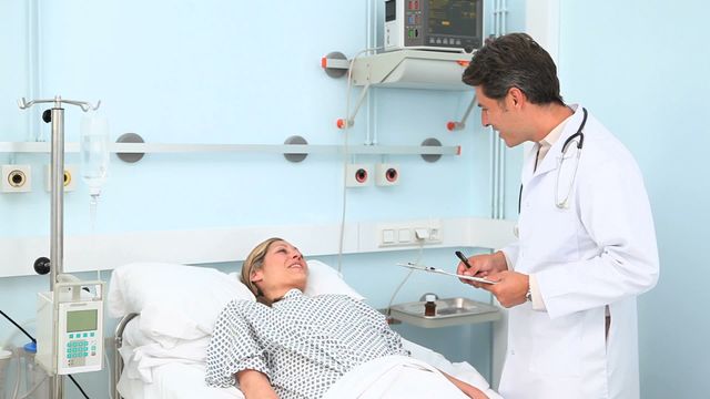 This video depicts a doctor consulting with a patient who is lying in a hospital bed. The patient is wearing a hospital gown and looks to be in stable condition. The doctor, holding a clipboard, appears to be discussing the patient's treatment plan. This video can be used in healthcare, medical consultations, and hospital care. It is ideal for illustrating doctor-patient interactions, professional healthcare services, and medical facilities.