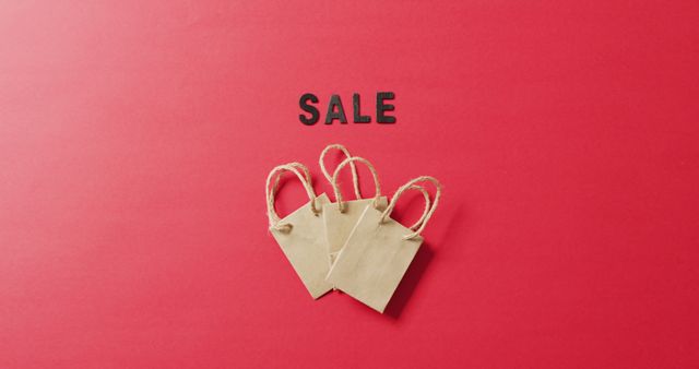 Sale in black letters with three brown gift bags on red background with copy space. Black friday, shopping, sale and retail concept digitally generated image.
