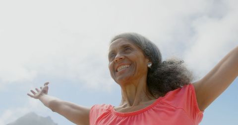 Joyful senior woman outdoors embracing life with open arms