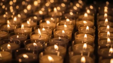 Shifting camera revealing rows of glass votive candles flickering in warm bokeh glow