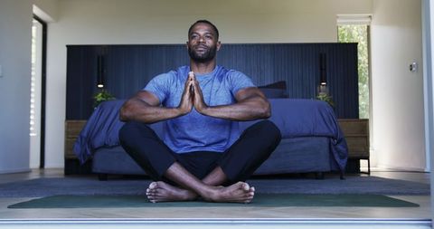 Mature man practicing yoga in minimalist bedroom, morning meditation and wellness at home