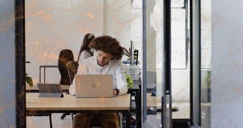 Working man typing on laptop in modern coworking office with glass partition and plants