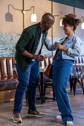 African american couple laughing and sharing coffee in modern cafe candid casual moment