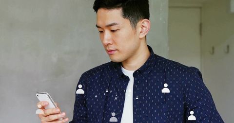 Asian Man Engaging with Smartphone in Modern Home Office