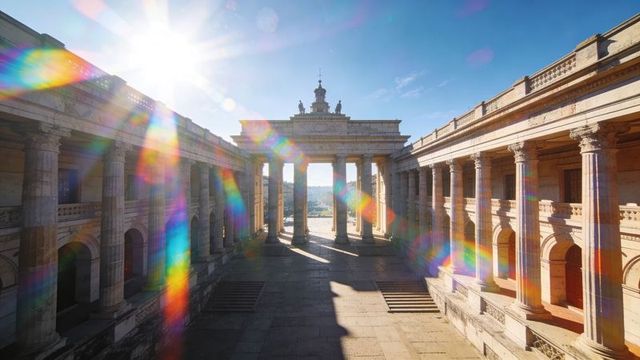 Sunlight streaming through neoclassical colonnade casting rainbow lens flare