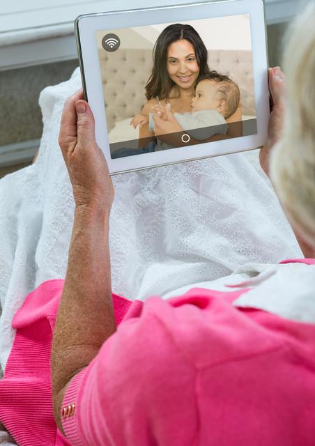 Rear view of senior woman having a video call with her daughter in digital tablet