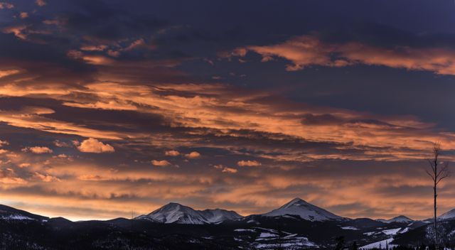 Majestic view of sunset above snow-covered mountain range with dramatic clouds in twilight sky. Ideal for travel websites, photography enthusiasts, desktop wallpapers, nature conservation projects, and landscape calendar. Perfect for highlighting natural beauty and serene landscapes.