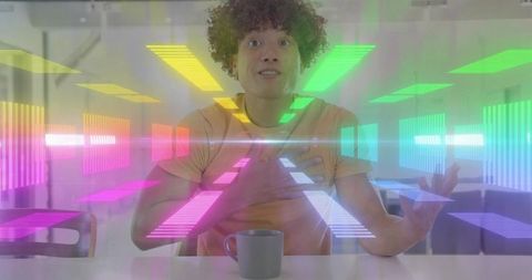 Young man gesturing at holographic neon interface during virtual classroom presentation