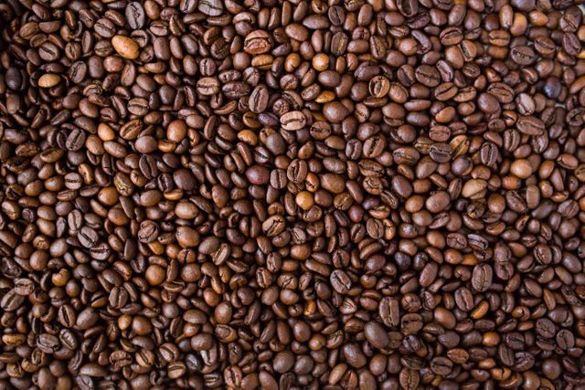 Detailed view of roasted coffee beans. Ideal for use in coffee shop promotions, packaging design, advertisements related to coffee products, or as a background in presentations and websites.