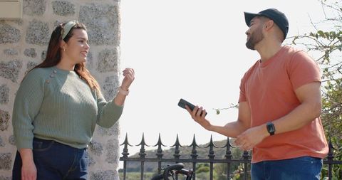 Two friends chatting at scenic overlook showing smartphone near bicycle and iron railing