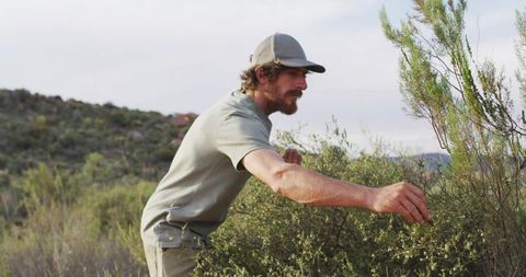Man observing bush in arid terrain with curiosity