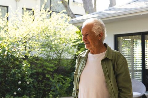 Senior Man Enjoying Tranquil Patio Near Blooming Shrubs