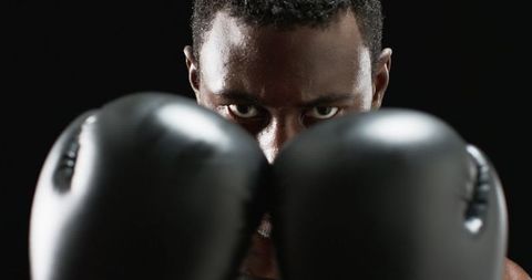 Intense boxer staring from behind gloves, determination and focused gaze