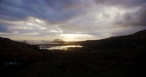 Sunset Rays Over Tranquil Coastal Channel with Distant Islands