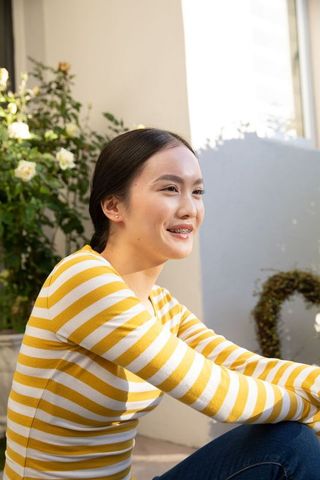 Young Woman Smiling Outdoors on Sunlit Balcony