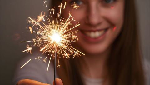 Smiling Woman Holding Lit Sparkler Celebrating Indoors Closeup Warm Bokeh Glow